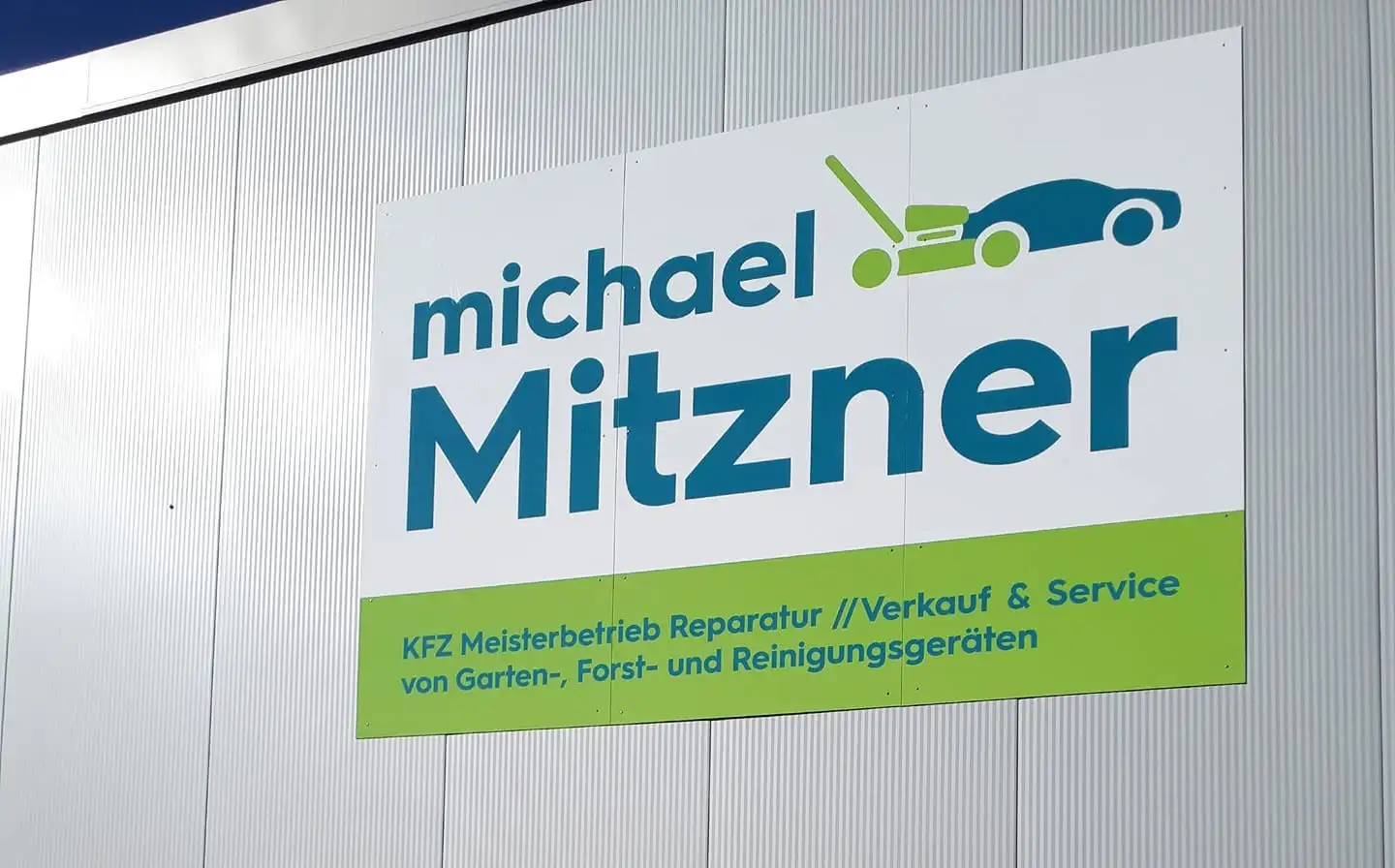 Weißes Firmenschild mit blau-grünem Schriftzug und Symbolen an einer hellen Hallenwand