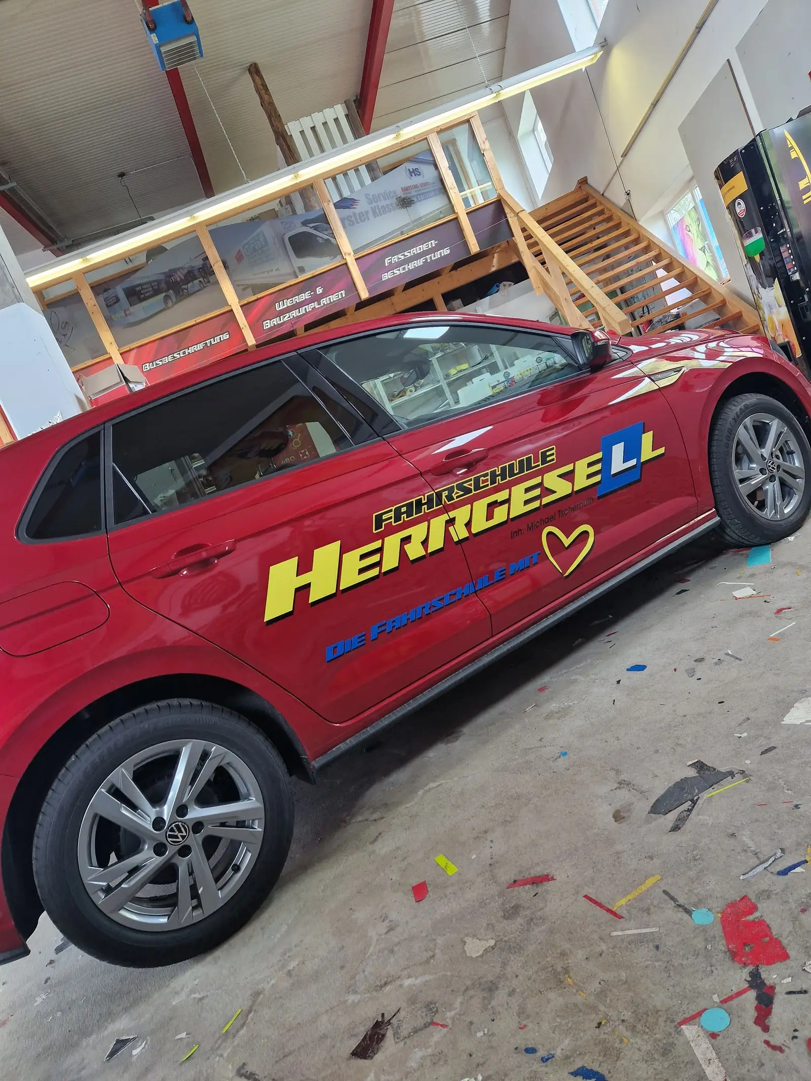 Roter Kleinwagen mit gelb-blauer Beschriftung in der Werkstatt von Schriften Tarmann