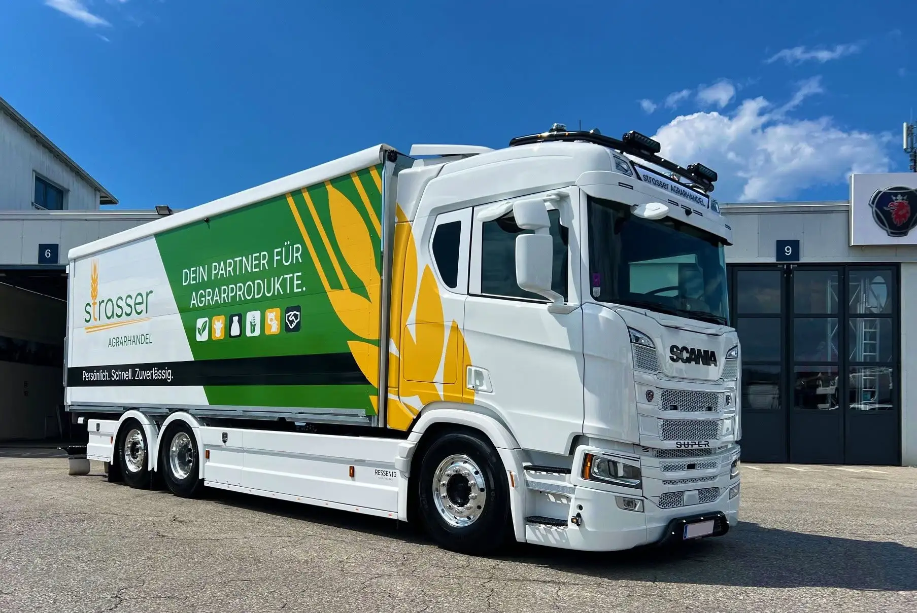 Weißer LKW im Freien mit grün-gelber Gestaltung über Kofferaufbau und Fahrerhaus