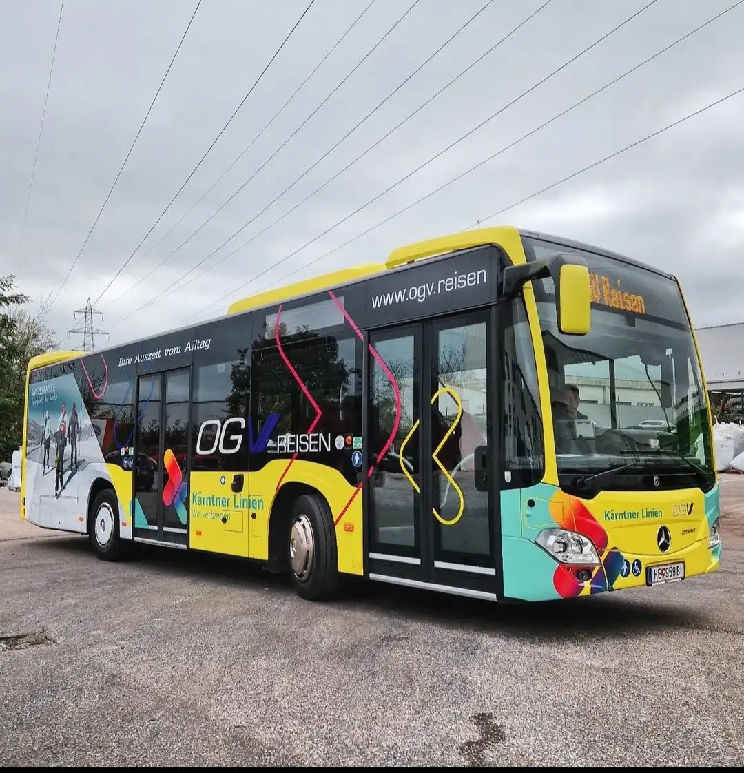 Gelb-türkiser Linienbus mit Schriftzügen und farbiger Gestaltung im Freien