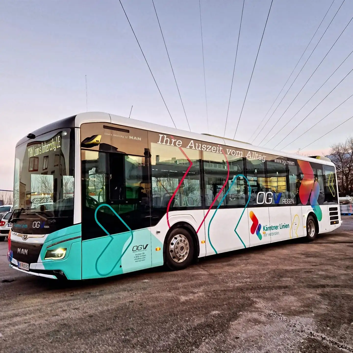 Weiß-türkiser Linienbus mit mehrfarbigem Dekor und Schriftzügen an der Seitenwand
