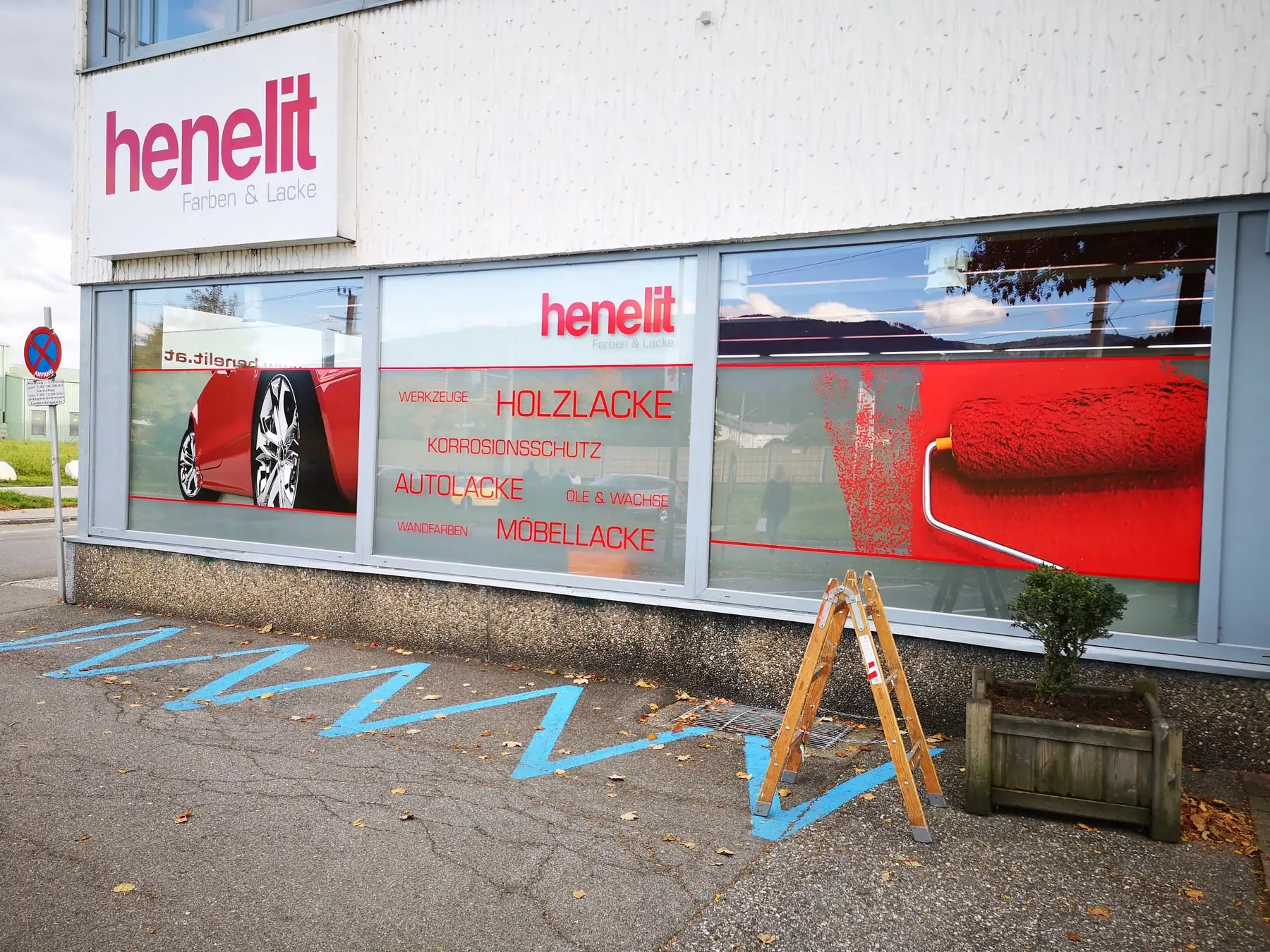 Schaufensterfront eines Fachgeschäfts, großflächig mit bedruckter Fensterfolie beklebt, darüber der Fassadenschriftzug